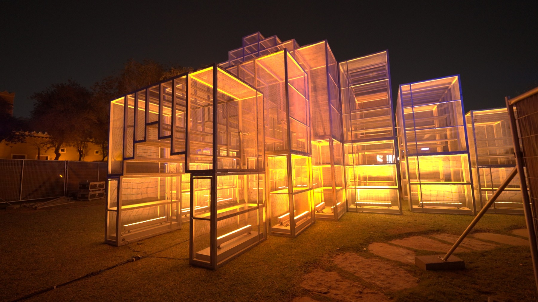 A walk-around light installation in Riyadh: stacked mesh cubes lit amber from within.
