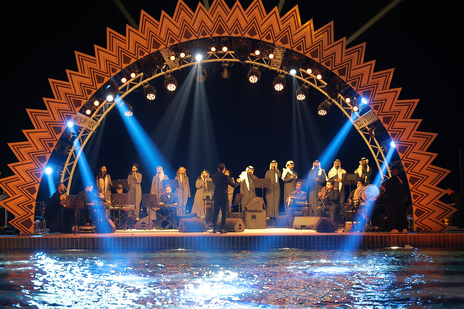 Singers and musicians performing on an amber and blue lit stage at the Saudi Air Navigation event in KAEC.